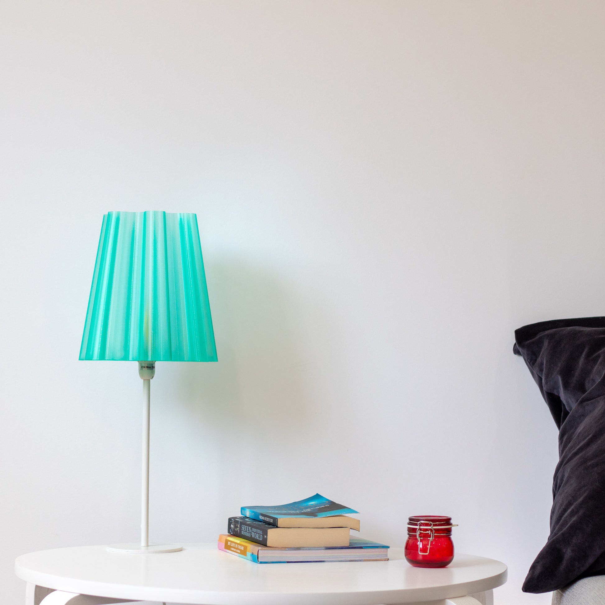 Translucent teal lamp shade with lights off, showcasing its sleek design and modern aesthetic on a minimalist bedside table. 3D printed semi-transparent lamp shade. Minimalistic looking lamp shades manufactured using 3D printing technology. Elevates the look of any room.