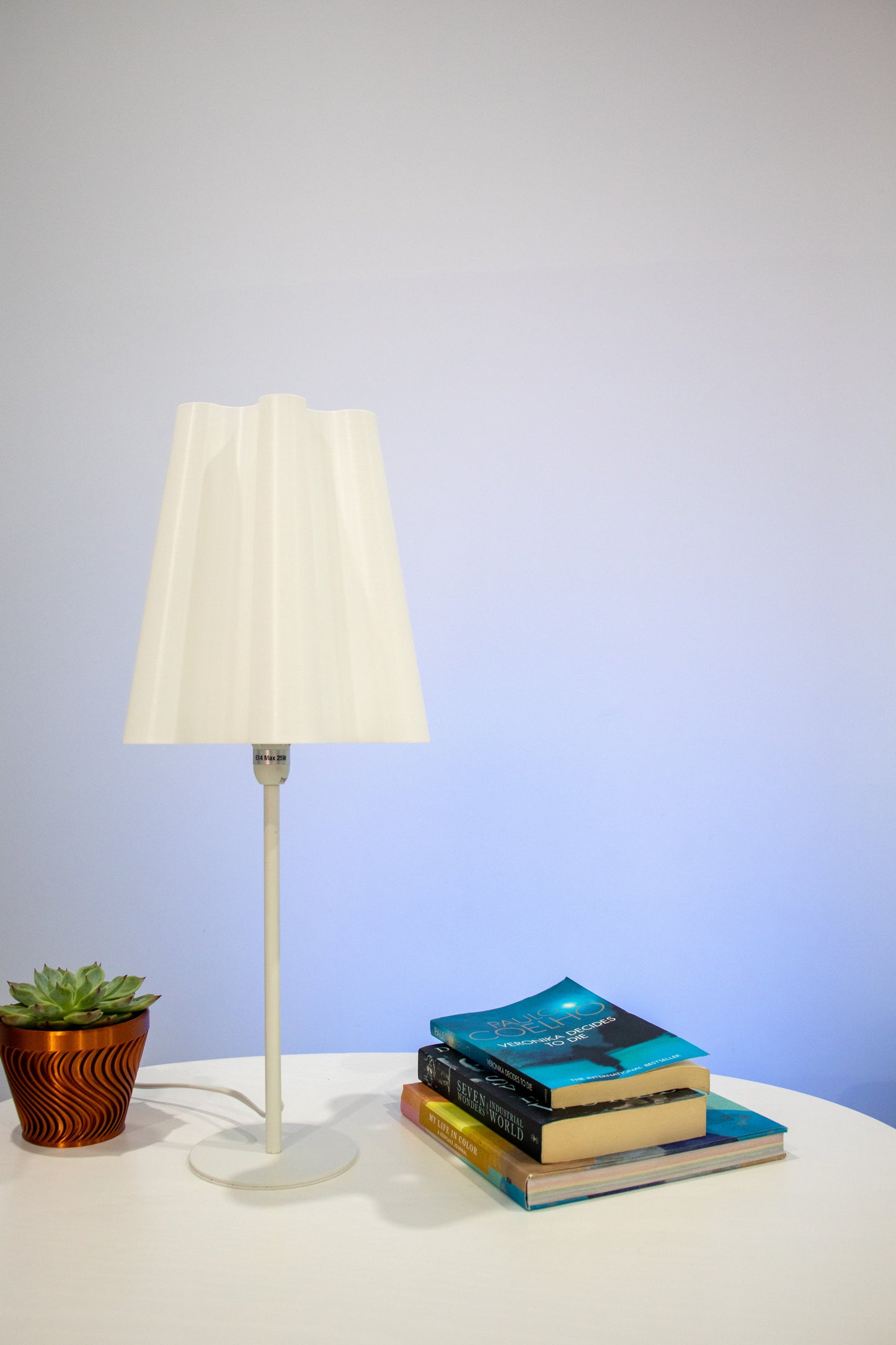 An aesthetic lamp with a wavy conical lamp shade in powered off state. The lamp elevates the looks of a modern minimalistic living space. The light colour is warm for reducing eye strain.